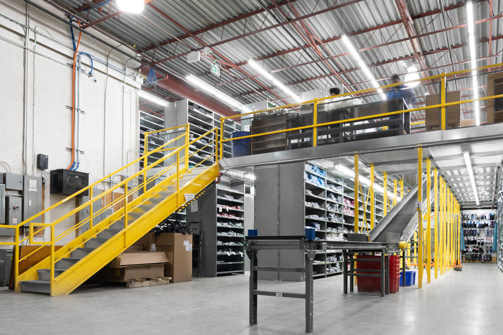 distribution center for varied sku and order picking in steel shelving with catwalk, staircases, structural support for work station mezzanine